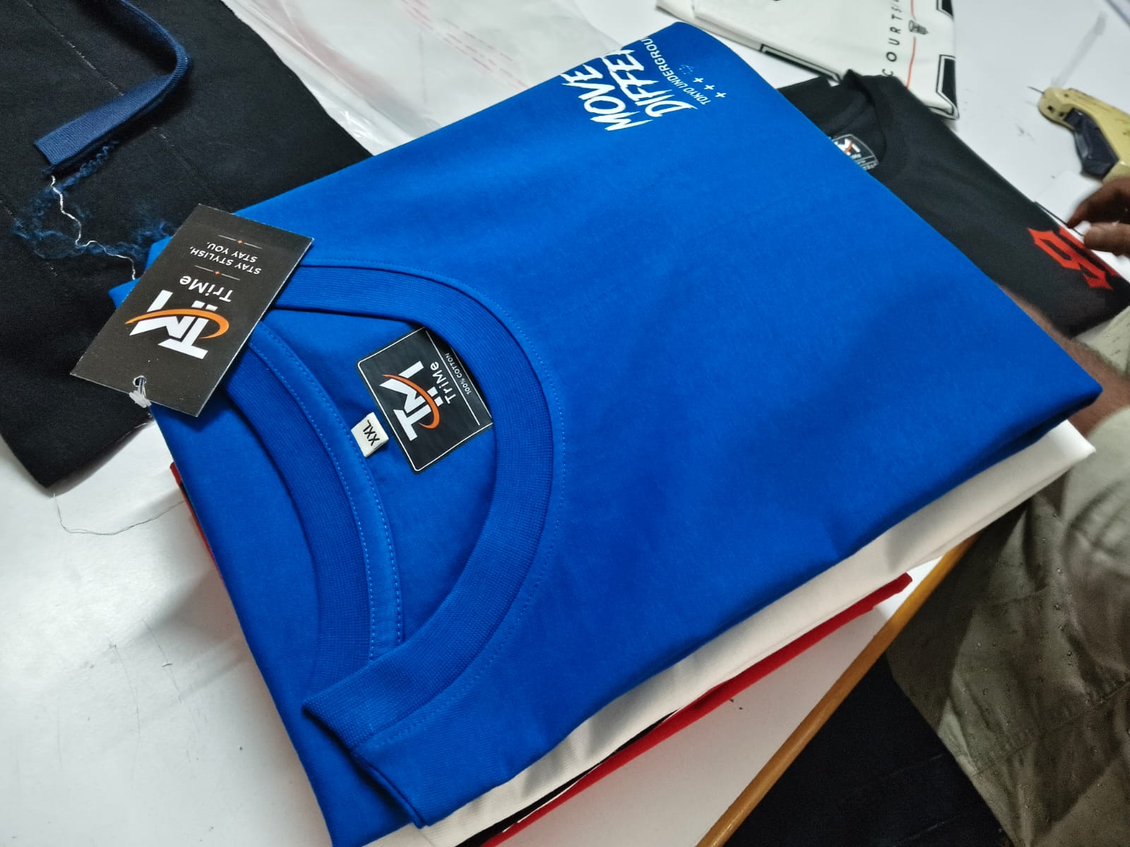 Folded blue TRI/ME 'Move Different' tee with hang tag