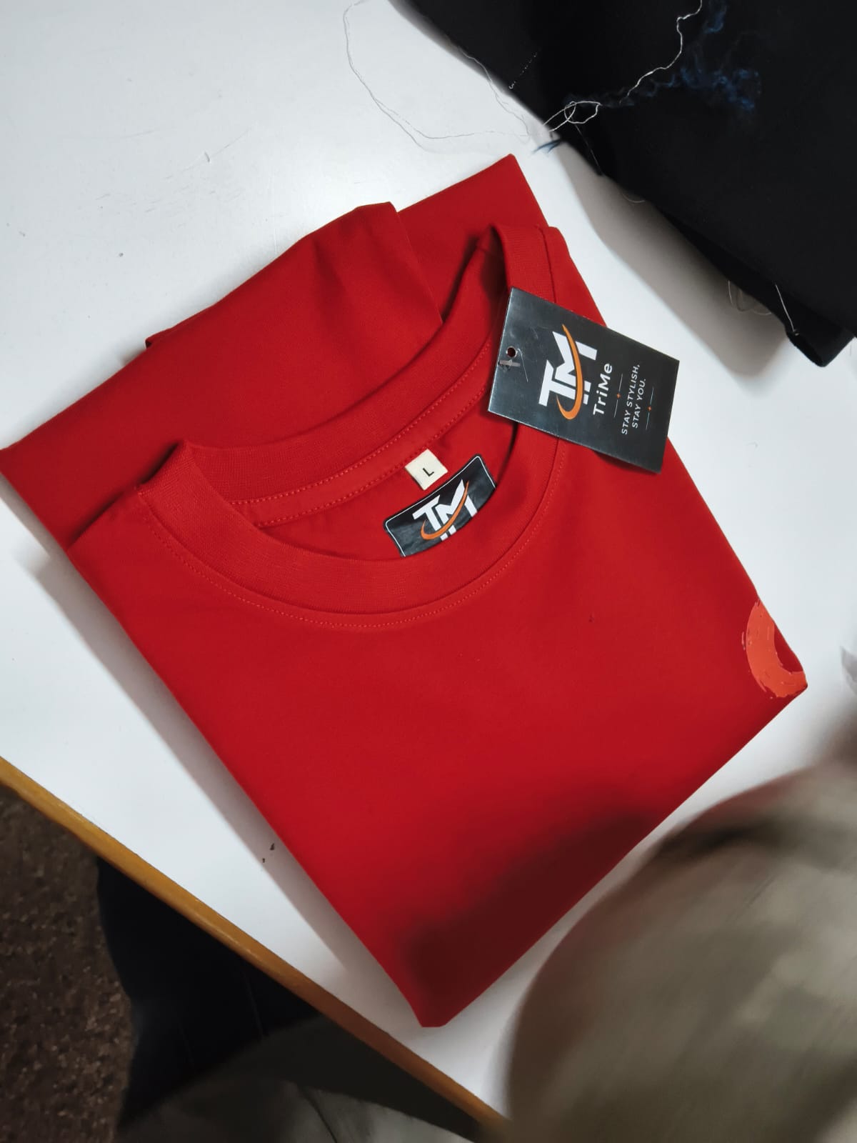 Folded red TRI/ME tee with branded hang tag